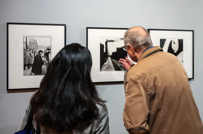 Museum Visitors Examining Black and White Urban Photography Exhibition