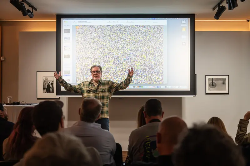 Hans-Jürgen Burkard at Leica Gallery Vienna. Hans-Jürgen Burkard Presenting at Leica Gallery Vienna, Arms Raised in Gesture