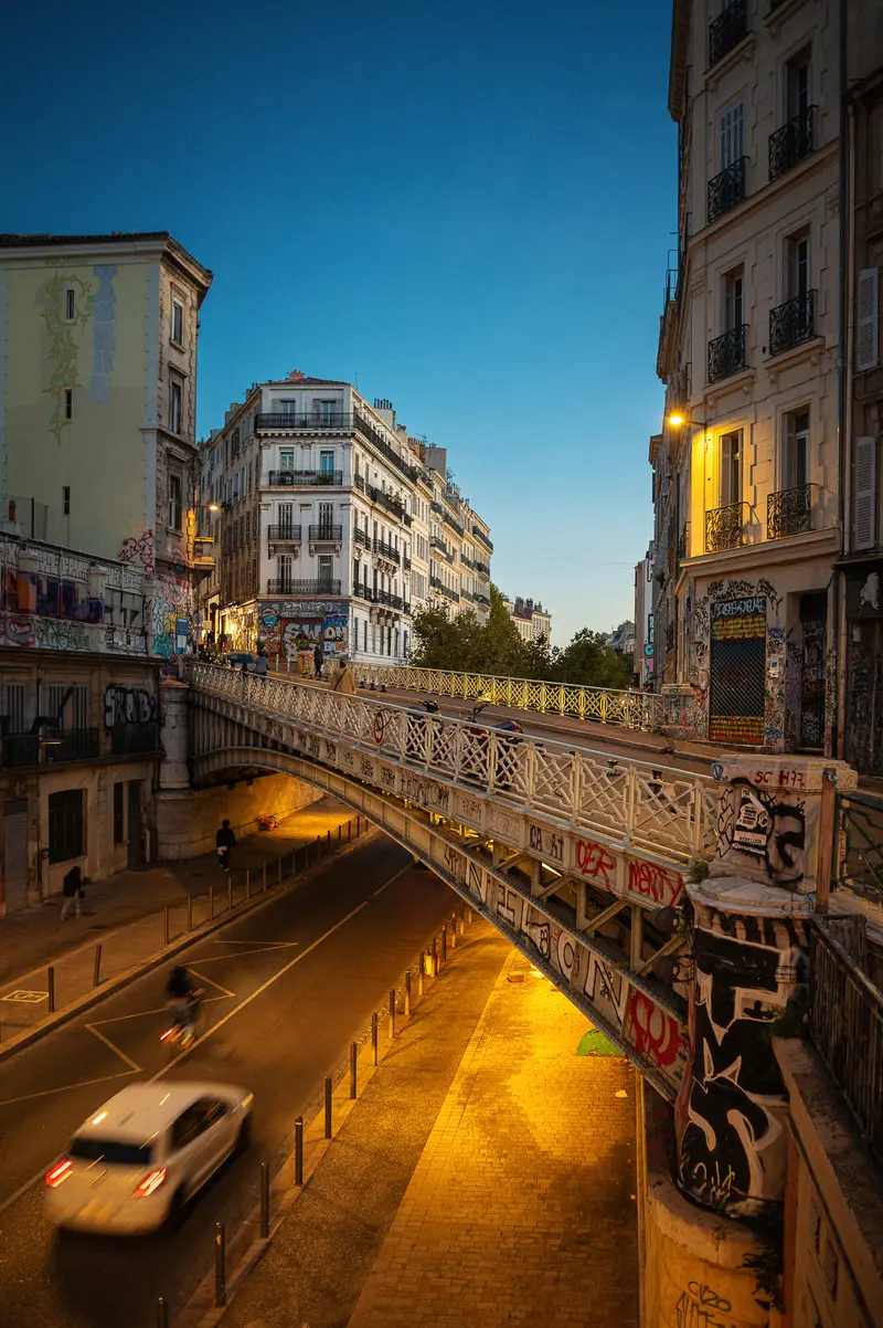 Marseille Urban Nightscape: Illuminated Bridge and Graffitied Street Scene