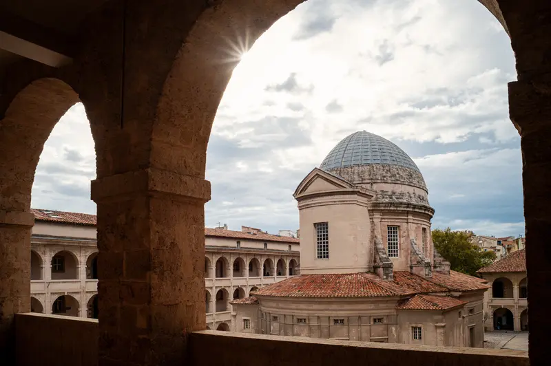 Sunlit Stone Arches Framing Baroque Dome in Historic Mediterranean Complex