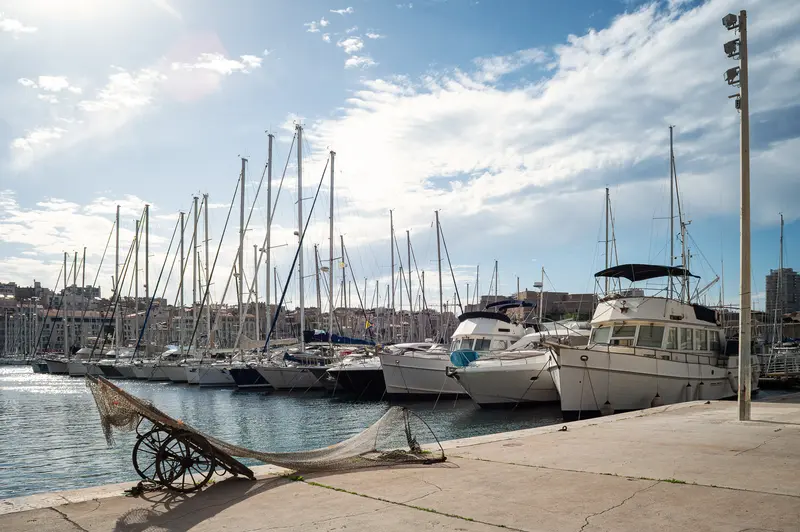Marseille Marina with Vintage Boat and Sailing Vessels under Cloudy Sky
