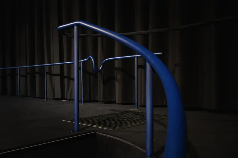 Blue Metallic Handrail and Grated Platform in Dark Urban Setting