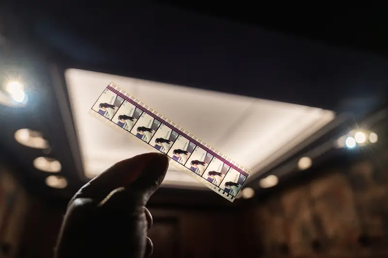 Analog Film Strip Examined Under Dramatic Lighting at Photography Archive