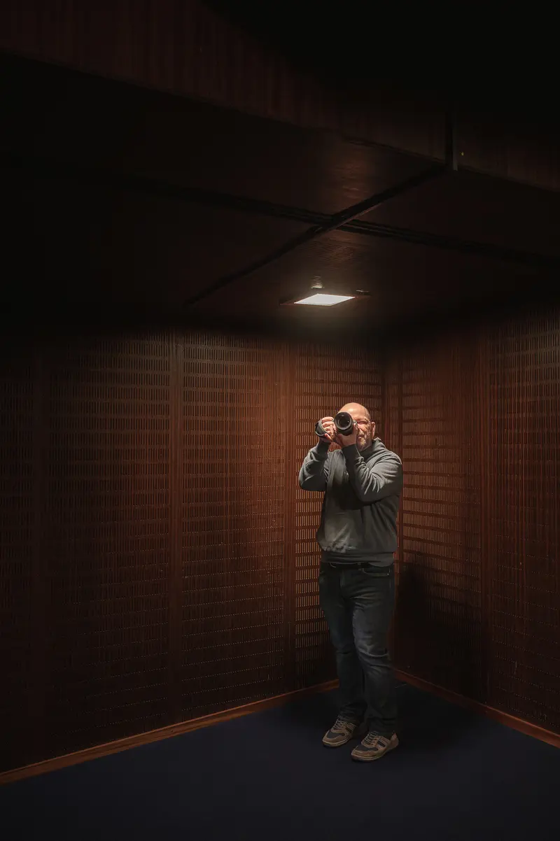 Photographer in Shadowy Corridor Capturing Moody Urban Portrait