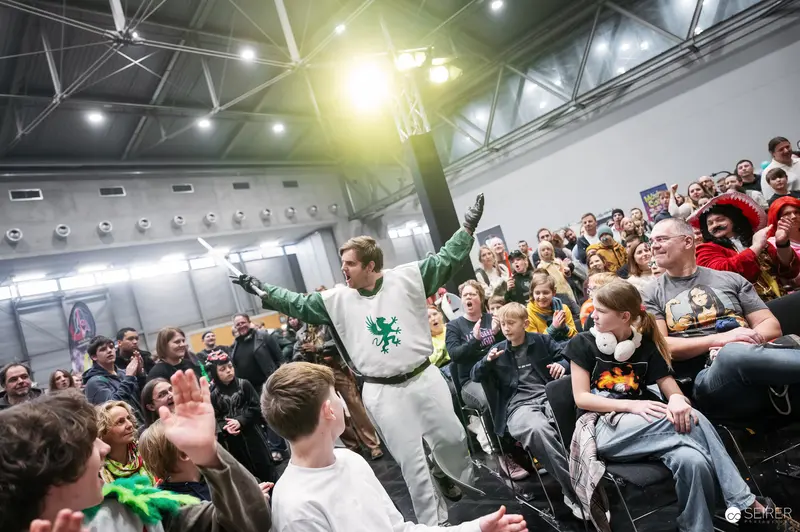 Performer in Green-Emblemed Costume at Vienna ComicCon 2025 Schaukampf