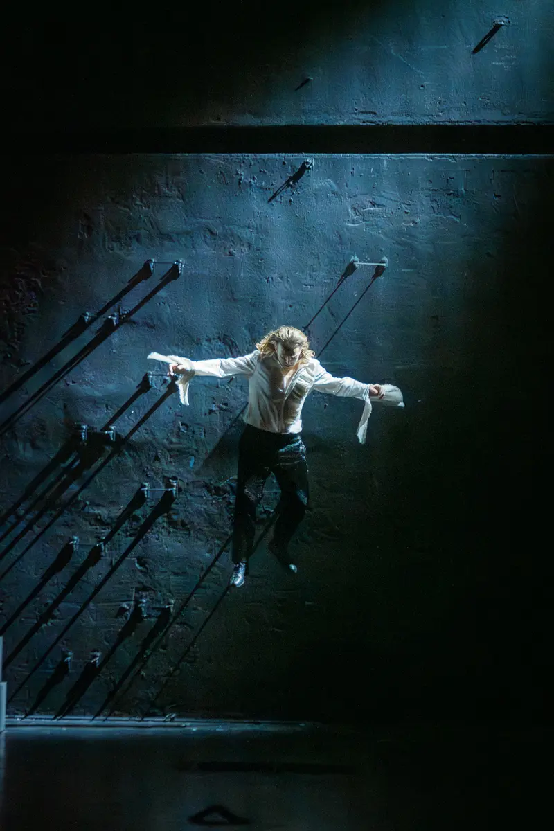 Hamlet Actor Suspended Against Dark Wall in Theatrical Performance