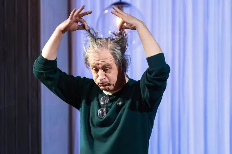 Performer in Dark Green Garment Making Horn Gesture at Kammerspiele der Josefstadt Vienna