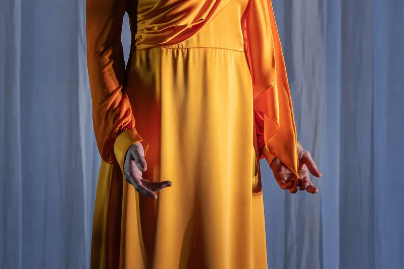 Actor in Yellow Dress with Orange Sleeves Holds Mobile Phone at Kammerspiele der Josefstadt