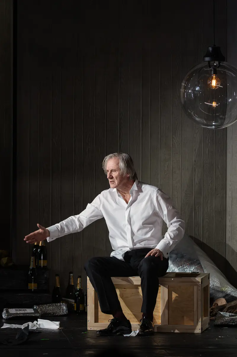 Actor in White Shirt Seated on Wooden Boxes in Theatrical Setting