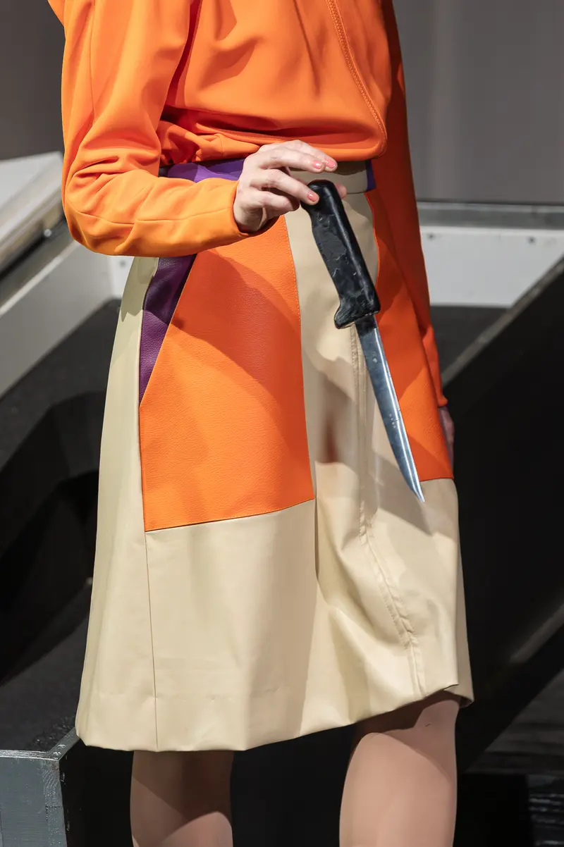 Actor in Orange Top and Beige Skirt Holding Microphone at Kammerspiele der Josefstadt