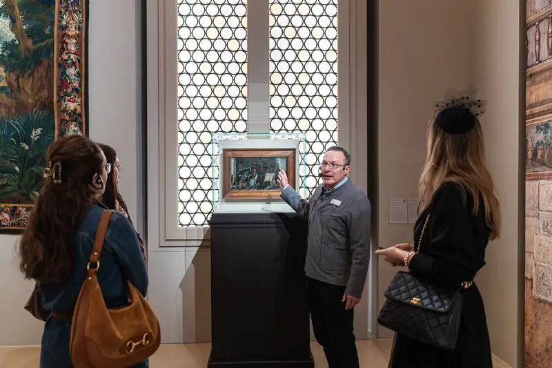 Museum Guide Presenting Framed Artwork to Visitors
