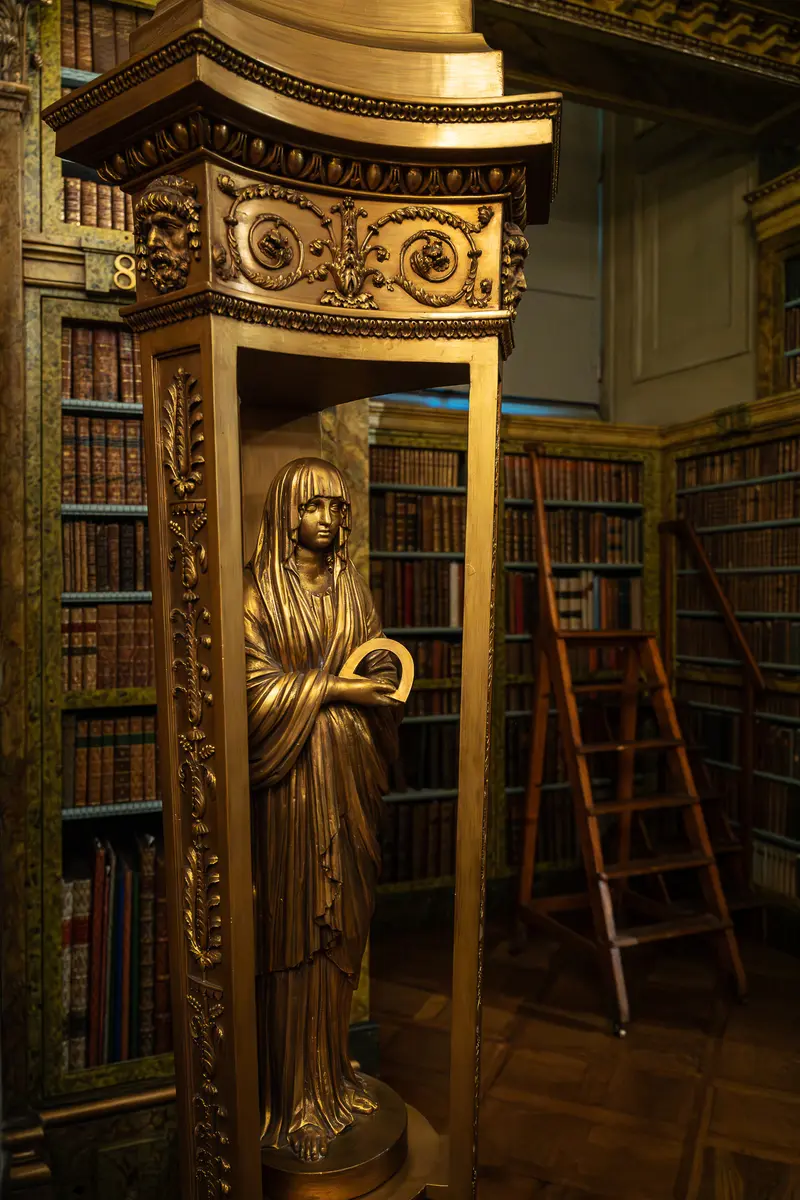 Gilded Wooden Statue in Historic Library with Mahogany Shelving