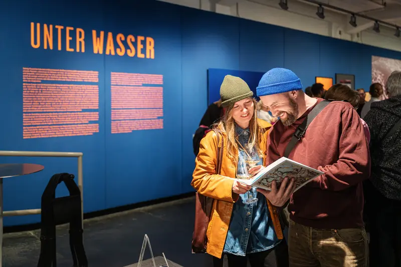 Museum Visitors Examine Exhibition Materials at "Unter Wasser" Display