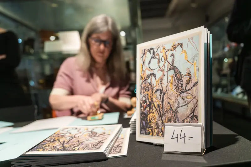Art Exhibition Viewing: Woman Examining Illustrated Catalog with Price Label