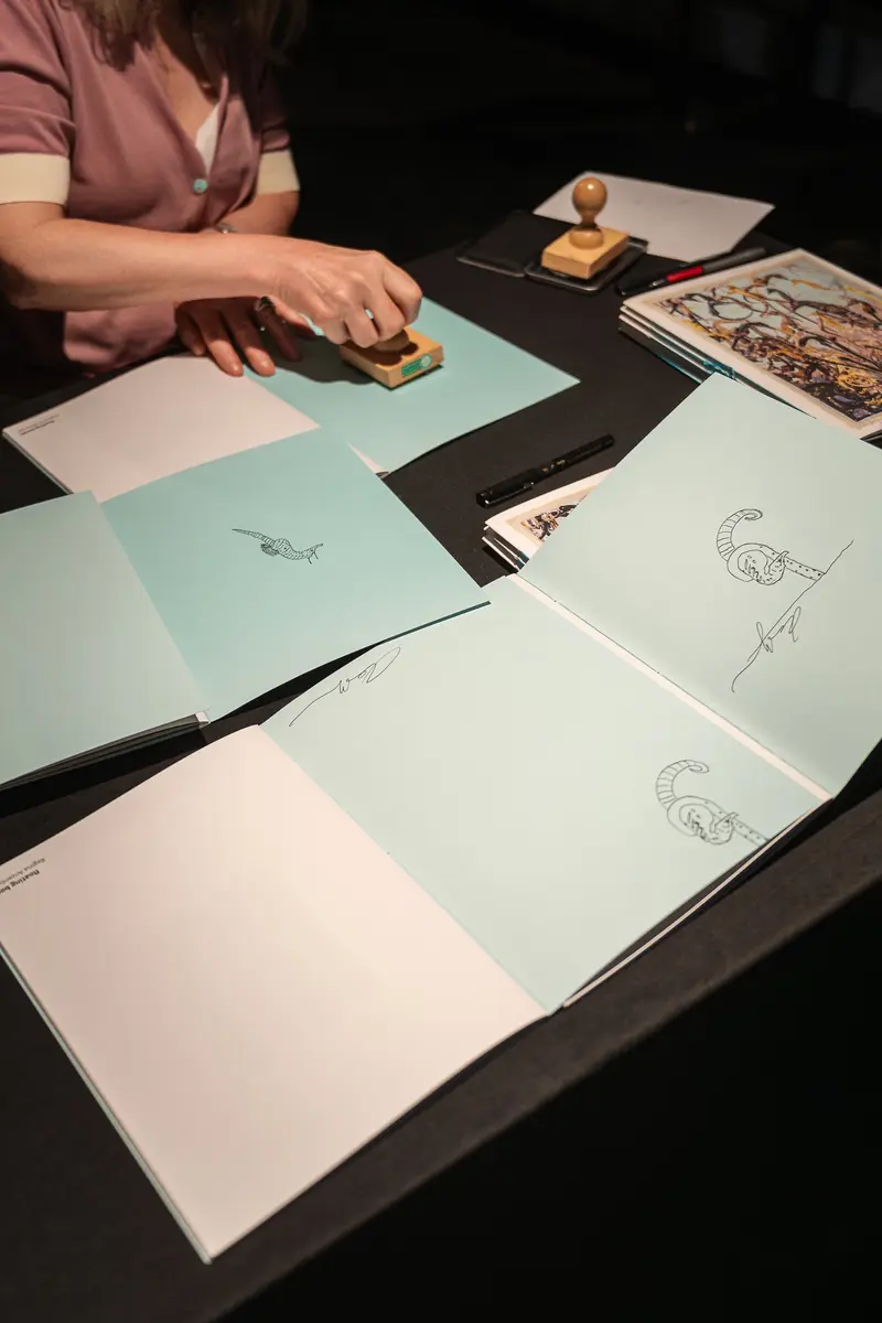 Artist Arranging Drawings and Stamps at Creative Workshop Table