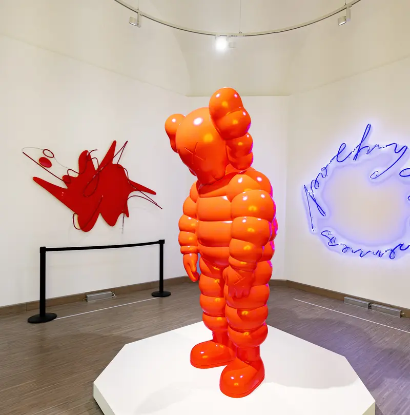 KAWS Orange Sculpture with Red Wall Installation and Blue Neon Text