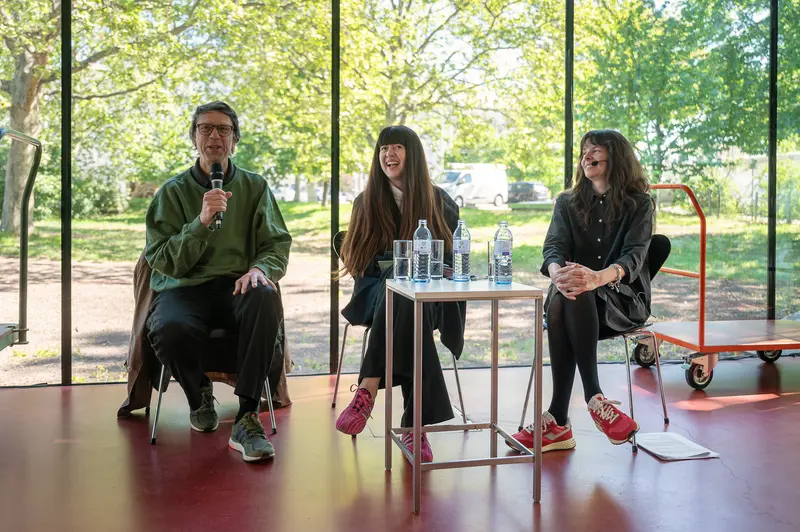 Panel discussion with three speakers seated before large windows overlooking park