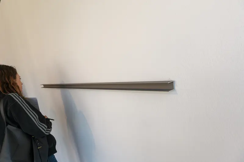 Woman Examining Minimalist Shelf Installation on Gallery Wall