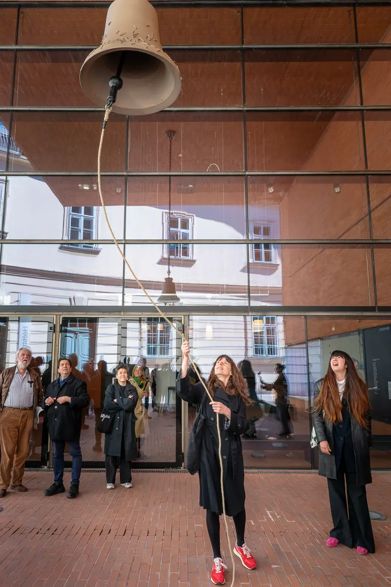 Group Performance with Suspended Bell Installation in Brick Courtyard