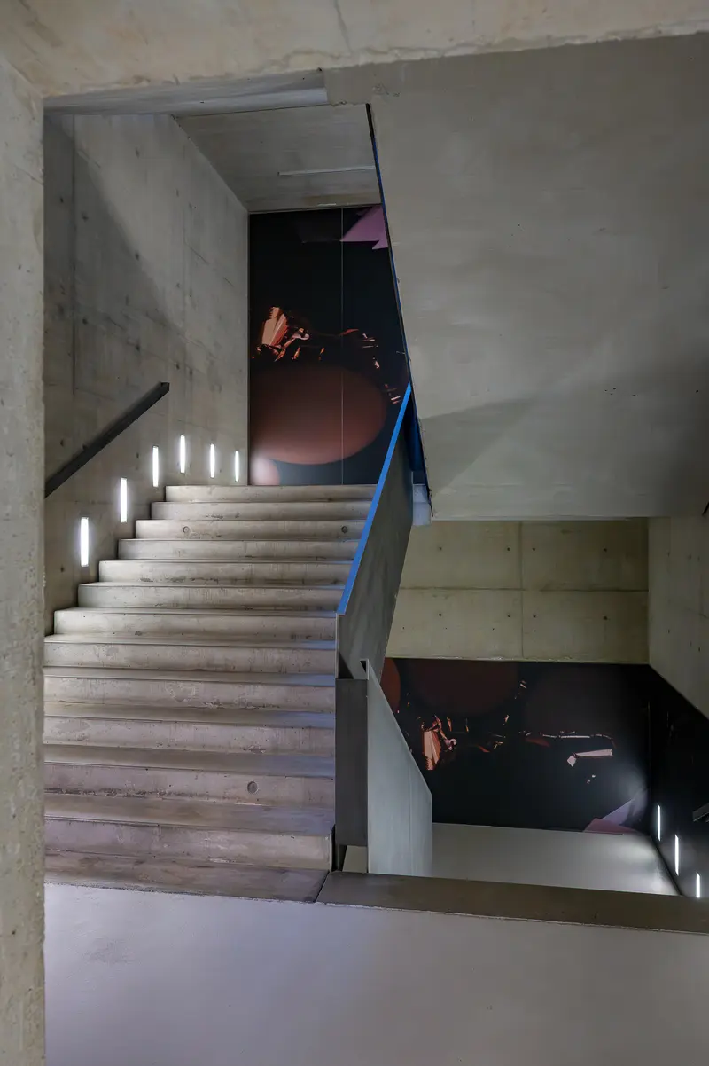 Concrete Stairwell with Blue Handrail and Stepped Lighting Installation
