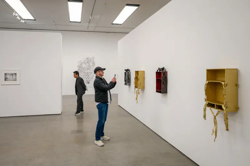 Contemporary Art Exhibition with Visitors Observing Wall-Mounted Installations
