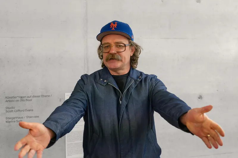 Artist in Blue Mets Cap Gesturing During Gallery Discussion