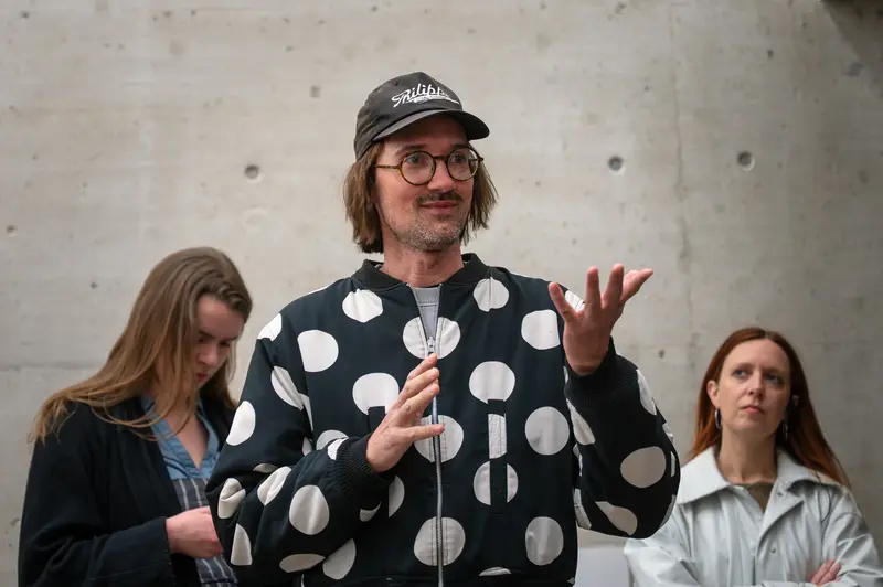 Man in Polka Dot Jacket Speaking at Event with Two Women