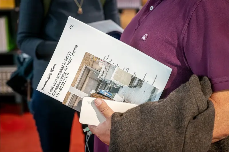 Visitor Examining Exhibition Brochure at Lebt und Arbeitet in Wien, Kunsthalle Wien