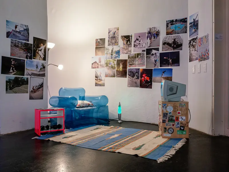Installation with Photographs, Blue Furniture, and Patterned Rug in Gallery Space