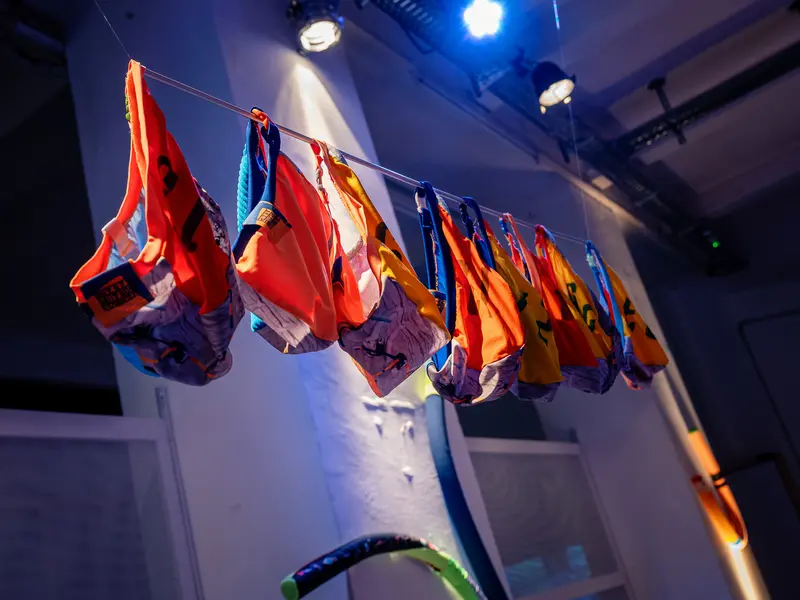 Colorful Life Jackets Hanging on Clothesline Under Gallery Lighting