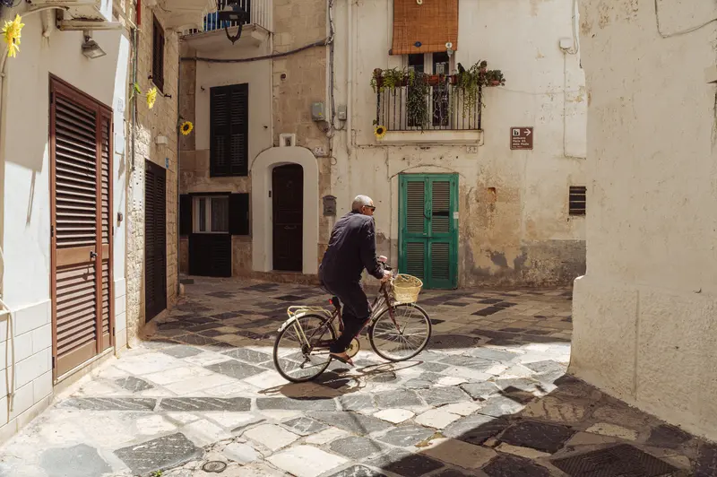 Man on Bicycle in Mediterranean Alleyway with Historic Architecture