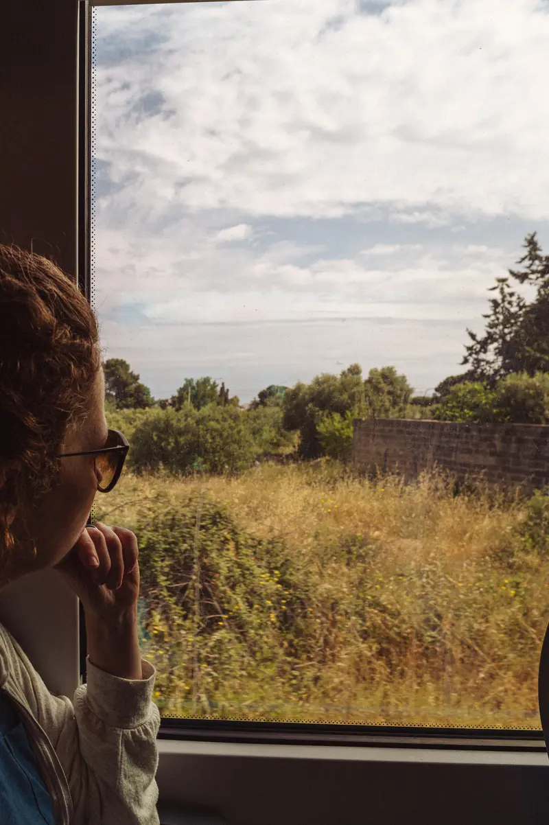 Passenger Gazing at Rural Landscape Through Train Window
