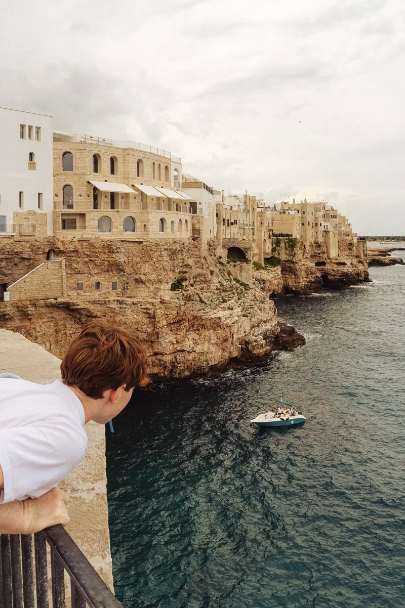 Tourist Overlooking Coastal Cliffs and Mediterranean Architecture