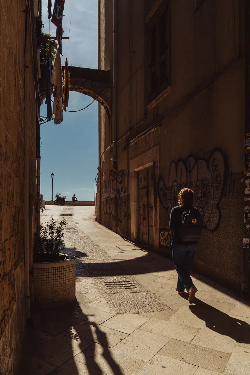 Pedestrian Walking Through Urban Alleyway with Graffiti
