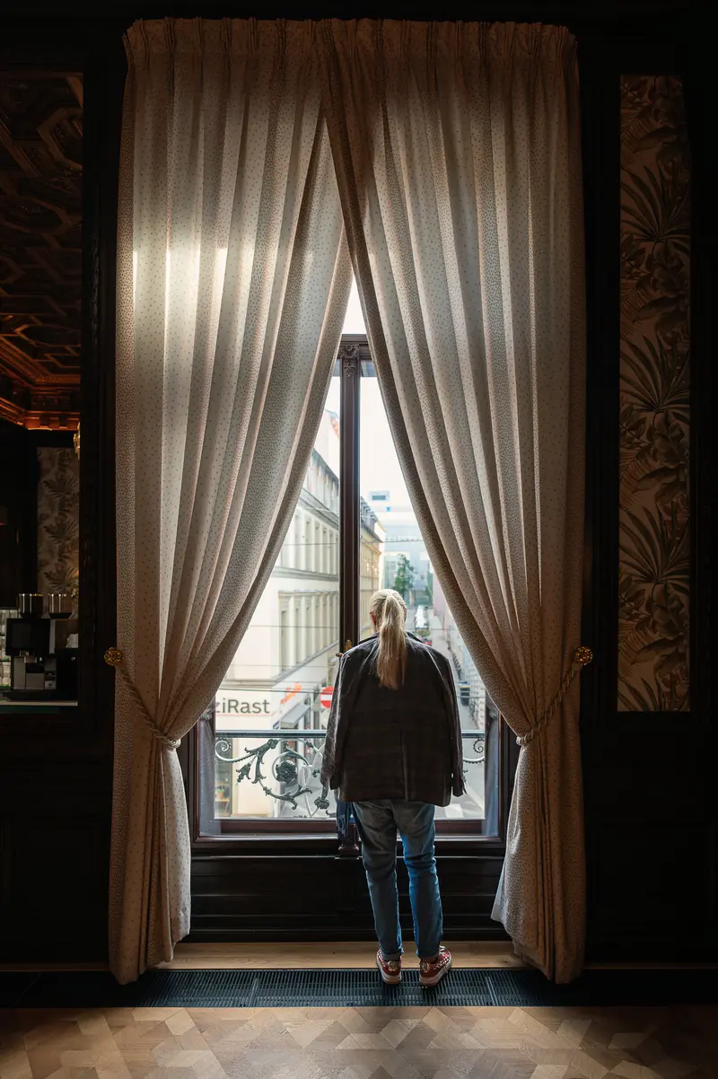 IgersWalk Participant Viewing Vienna Streetscape Through Palais Chotek Curtains