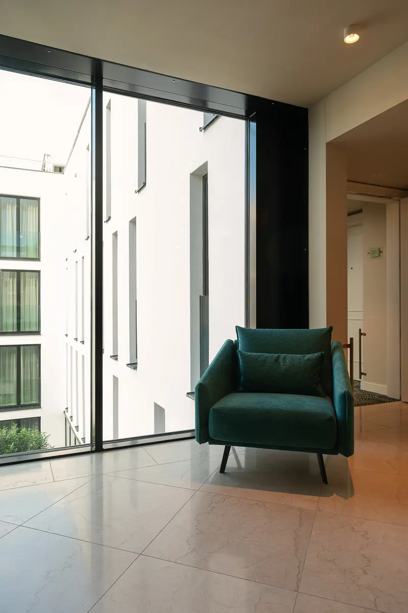 Modern Interior at IgersWalk Vienna 2026: Teal Chair by Floor-to-Ceiling Windows