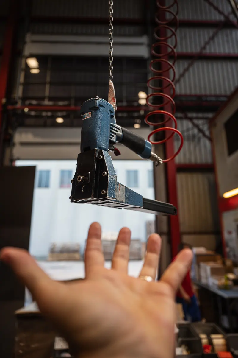 Suspended strapping tool above outstretched hand at Frankstahl warehouse