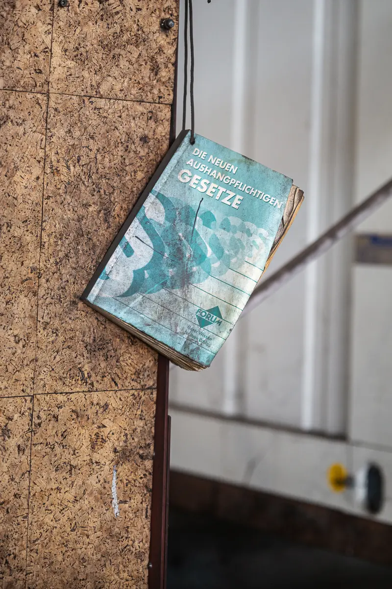 Worn Austrian labour law booklet hanging on a cork board at Frankstahl
