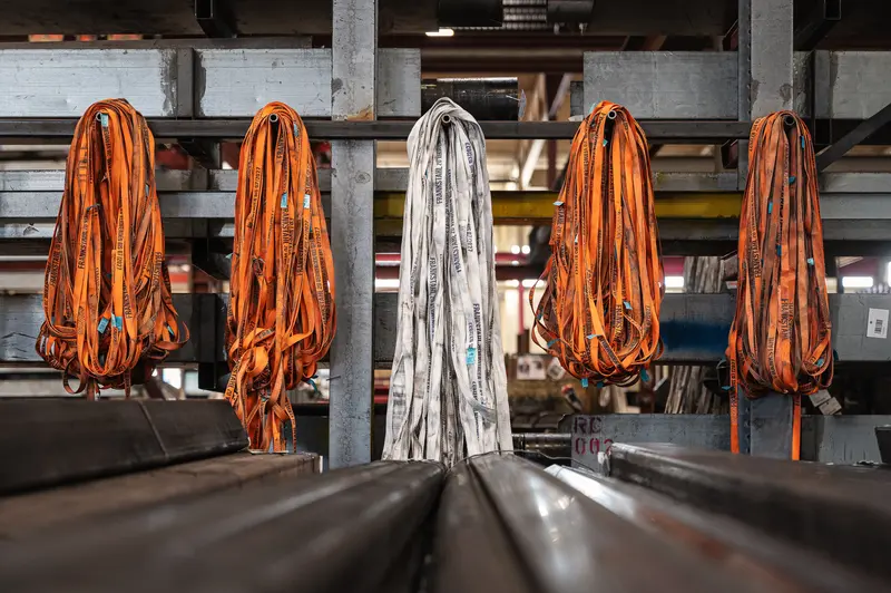Orange and white lifting slings hanging in Frankstahl steel warehouse