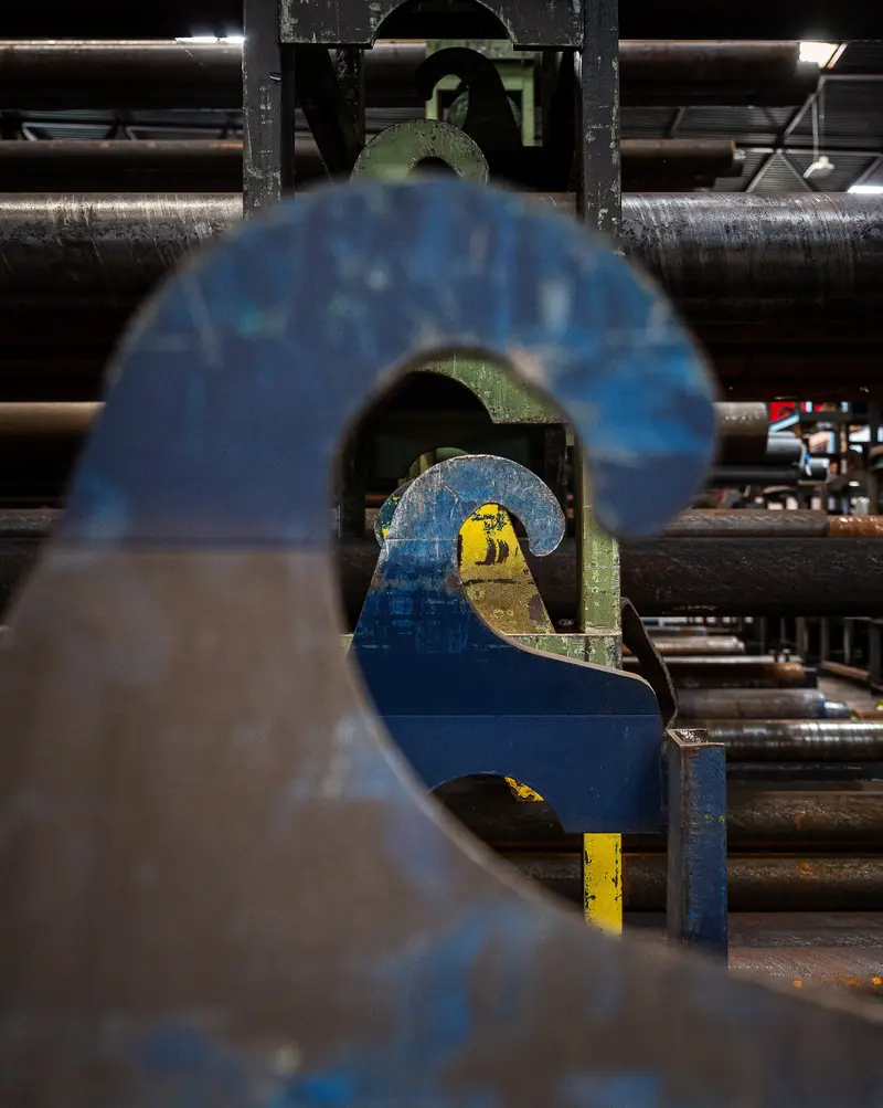 Mill-scale blue pipe clamps frame steel tube bundles on warehouse floor