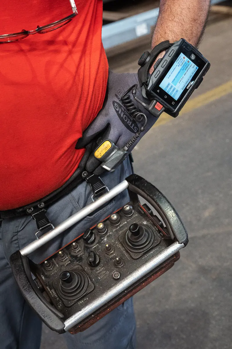 Frankstahl worker holds crane remote control and barcode scanner terminal
