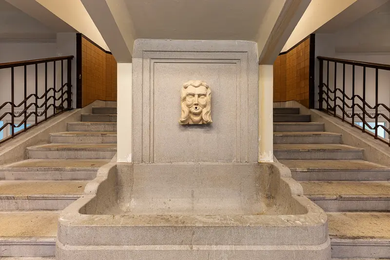 Stone fountain mask at the foot of the Amalienbad staircase, Vienna