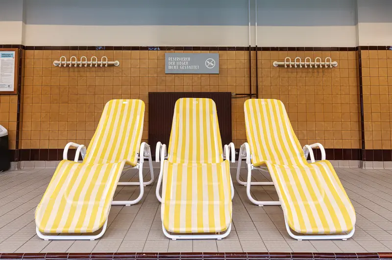 Yellow-striped sun loungers on the poolside terrace of Amalienbad Vienna