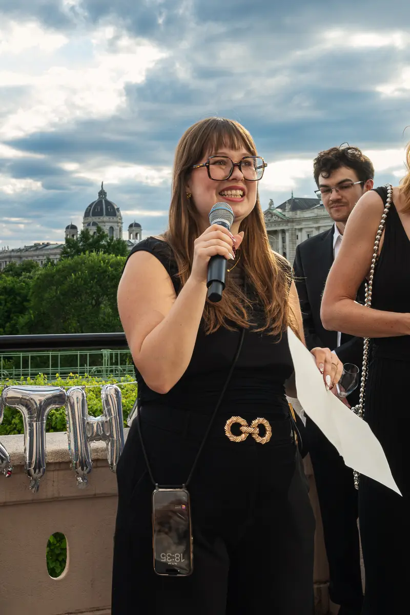 Woman Speaking at Rooftop Event with Vienna Kunsthistorisches Museum Backdrop