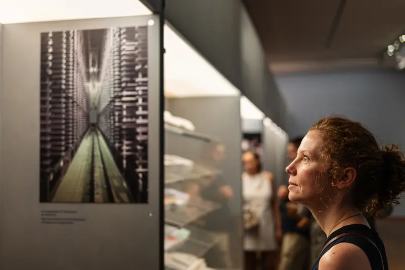 Visitor Examining Archival Storage Photograph at Exhibition