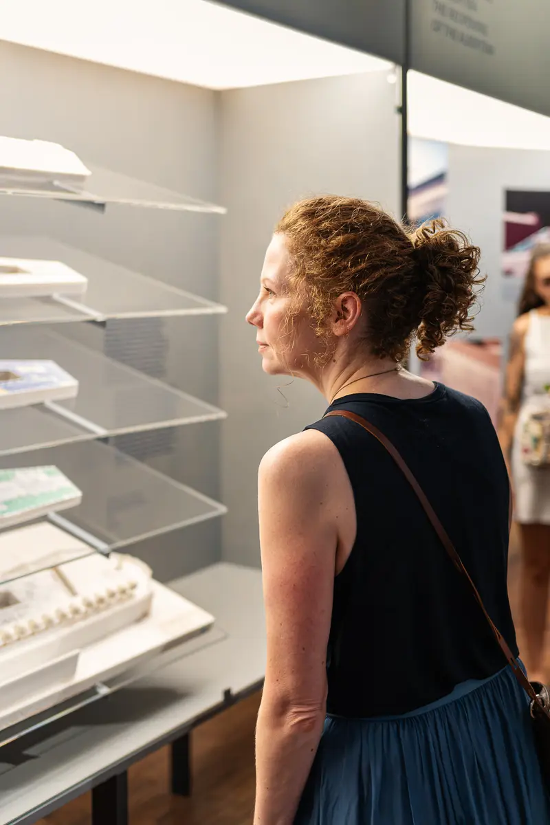 Visitor Examining Architectural Model and Publications at Gallery Exhibition
