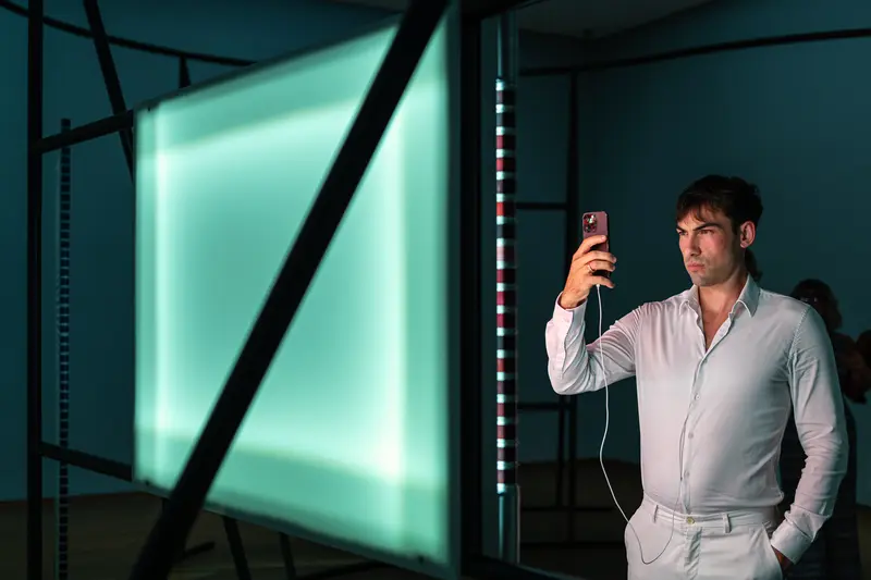 Visitor Photographing Neon Light Installation at Contemporary Art Exhibition