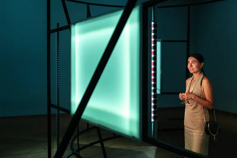 Visitor Contemplating Neon Light Installation in Darkened Gallery
