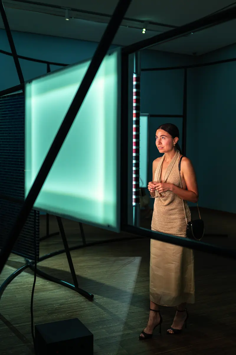 Visitor Standing Before Illuminated Light Installation in Dark Gallery Space