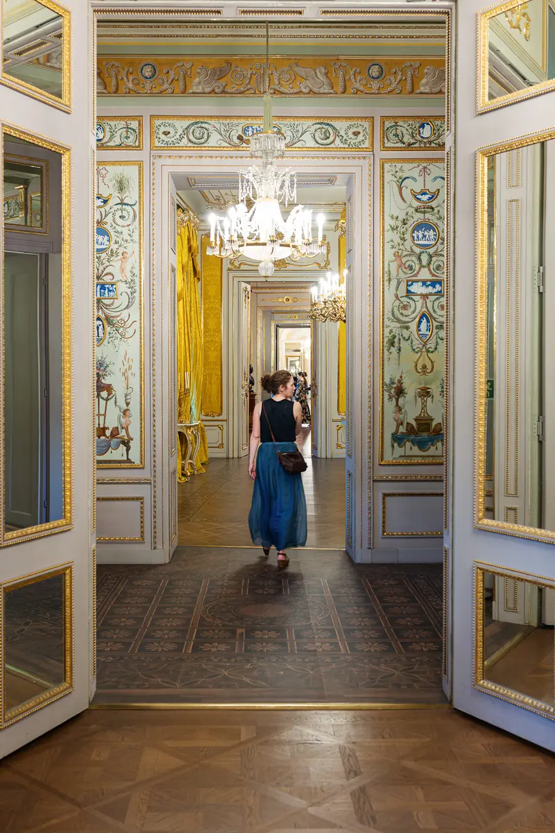 Visitor Walking Through Ornate Mirrored Enfilade of Historic Palace Interior